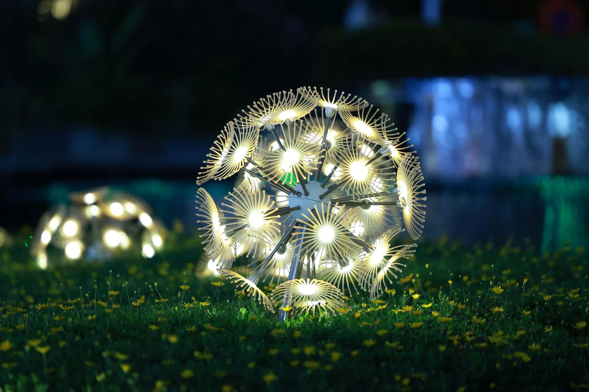 Sculptural LED garden light glowing on a lawn at night